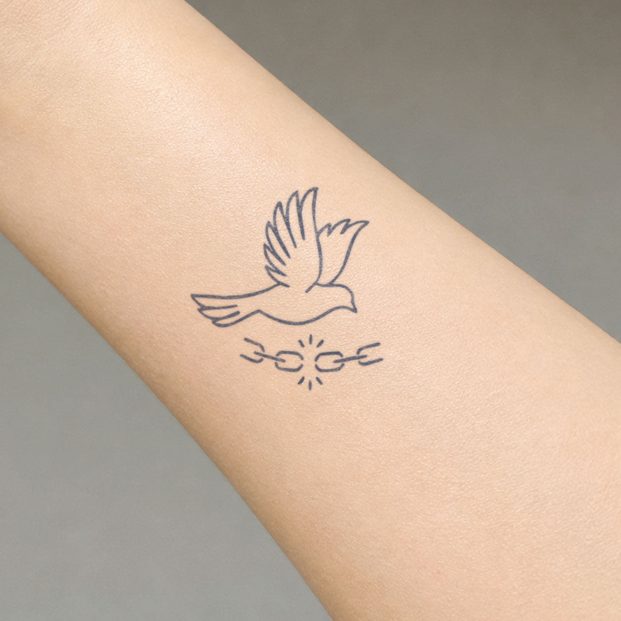 Bird temporary tattoo featuring a flying dove above broken chains, symbolizing freedom on the inner forearm.
