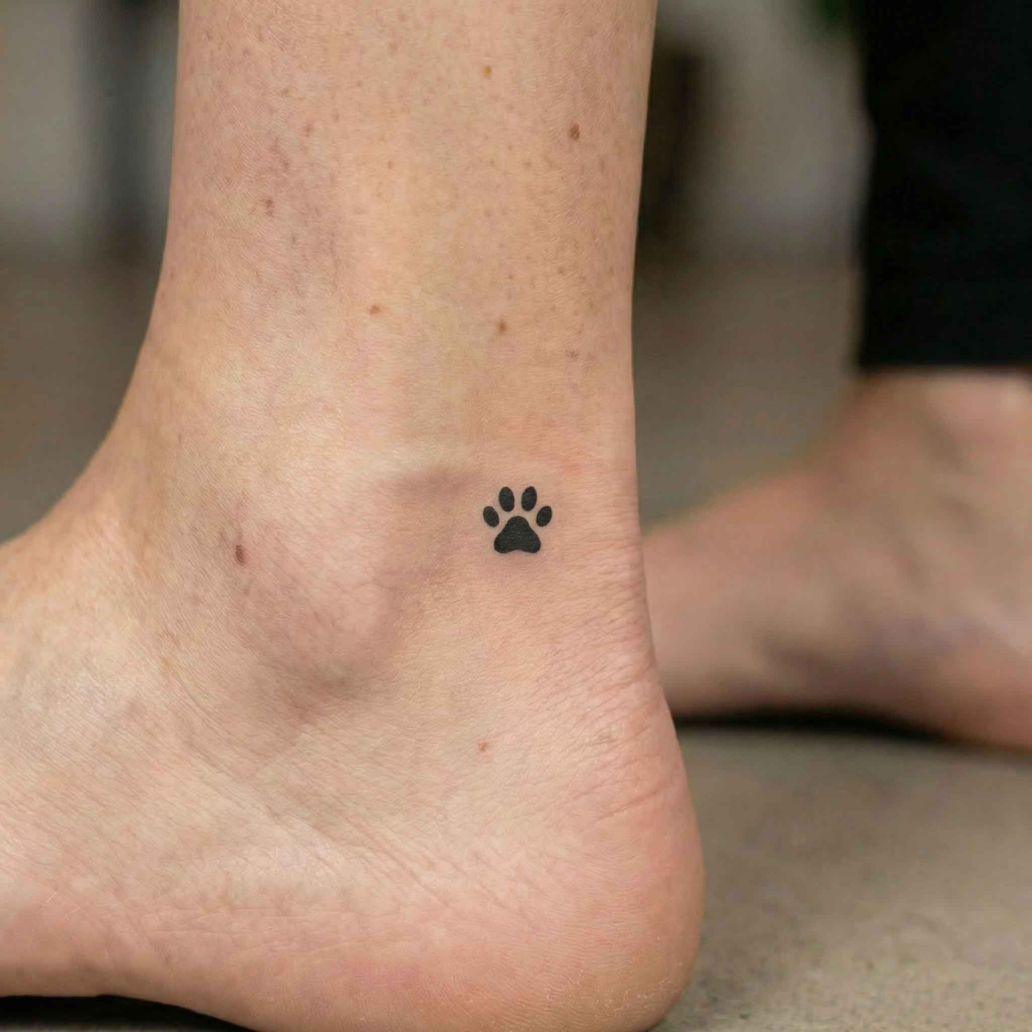 Small paw print 2 week temp tattoo worn on ankle with simple pet lover style