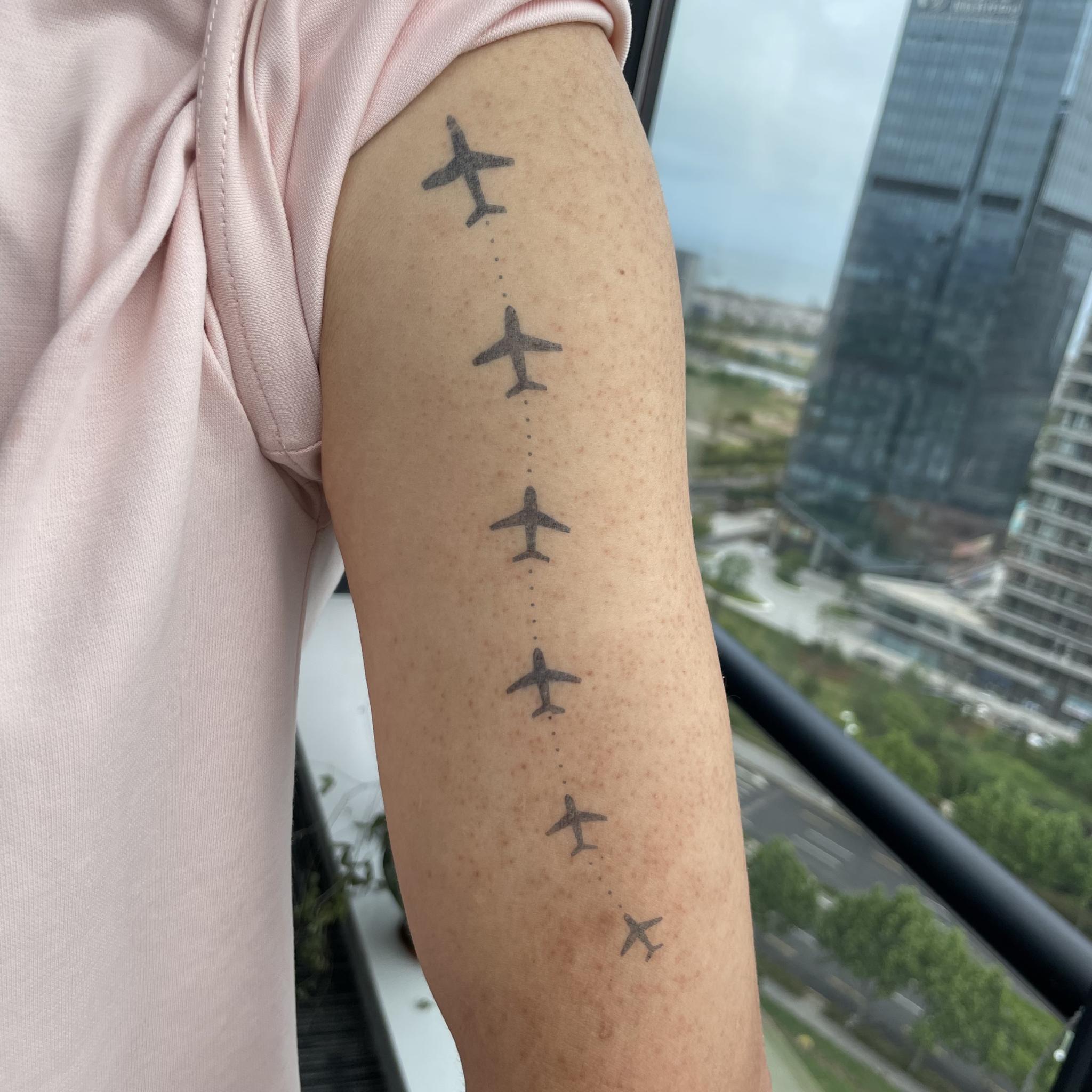Travel tattoo featuring airplane flight path design on upper arm