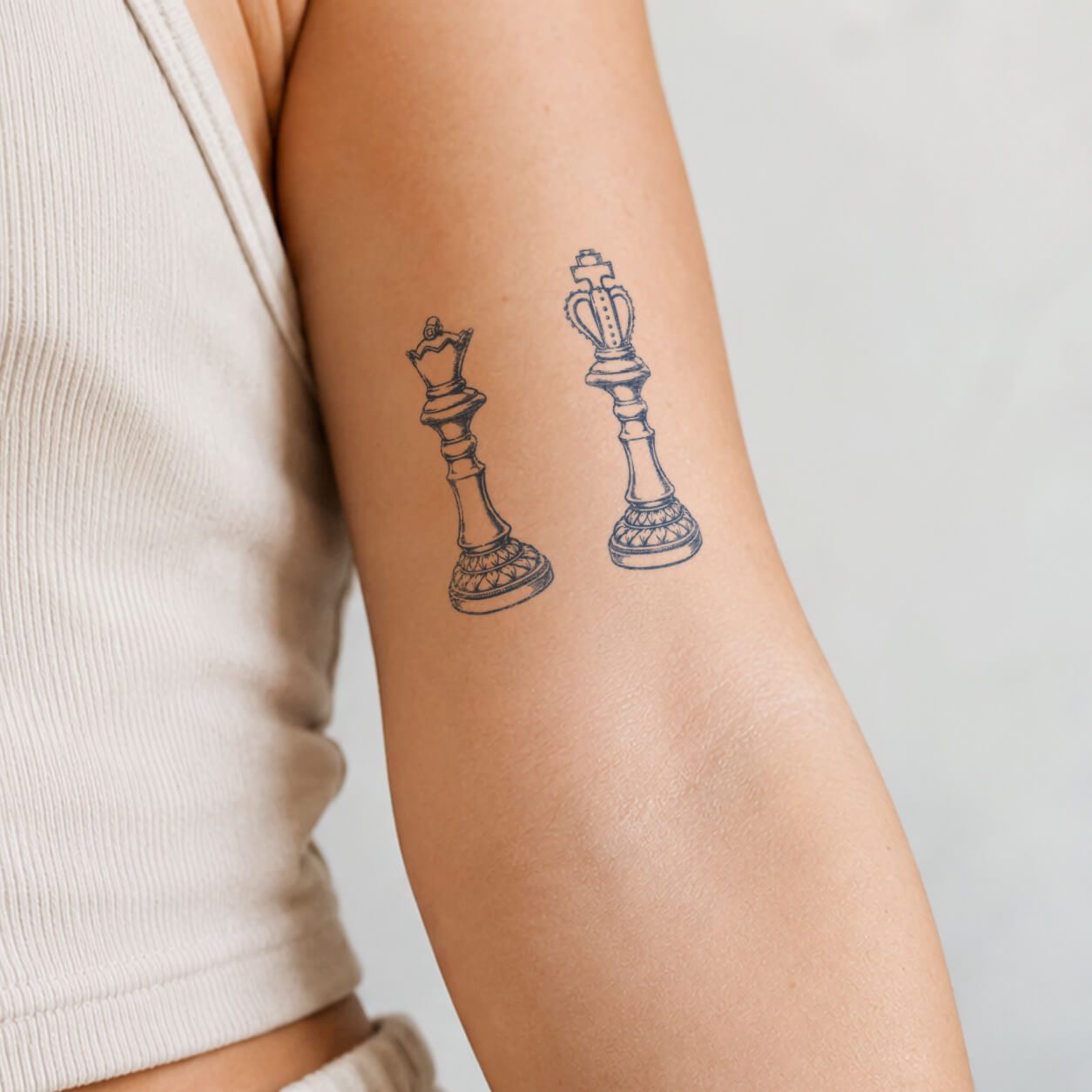 Vintage chess piece temporary tattoo featuring detailed king and queen figures with classic engraved line art style on the upper arm