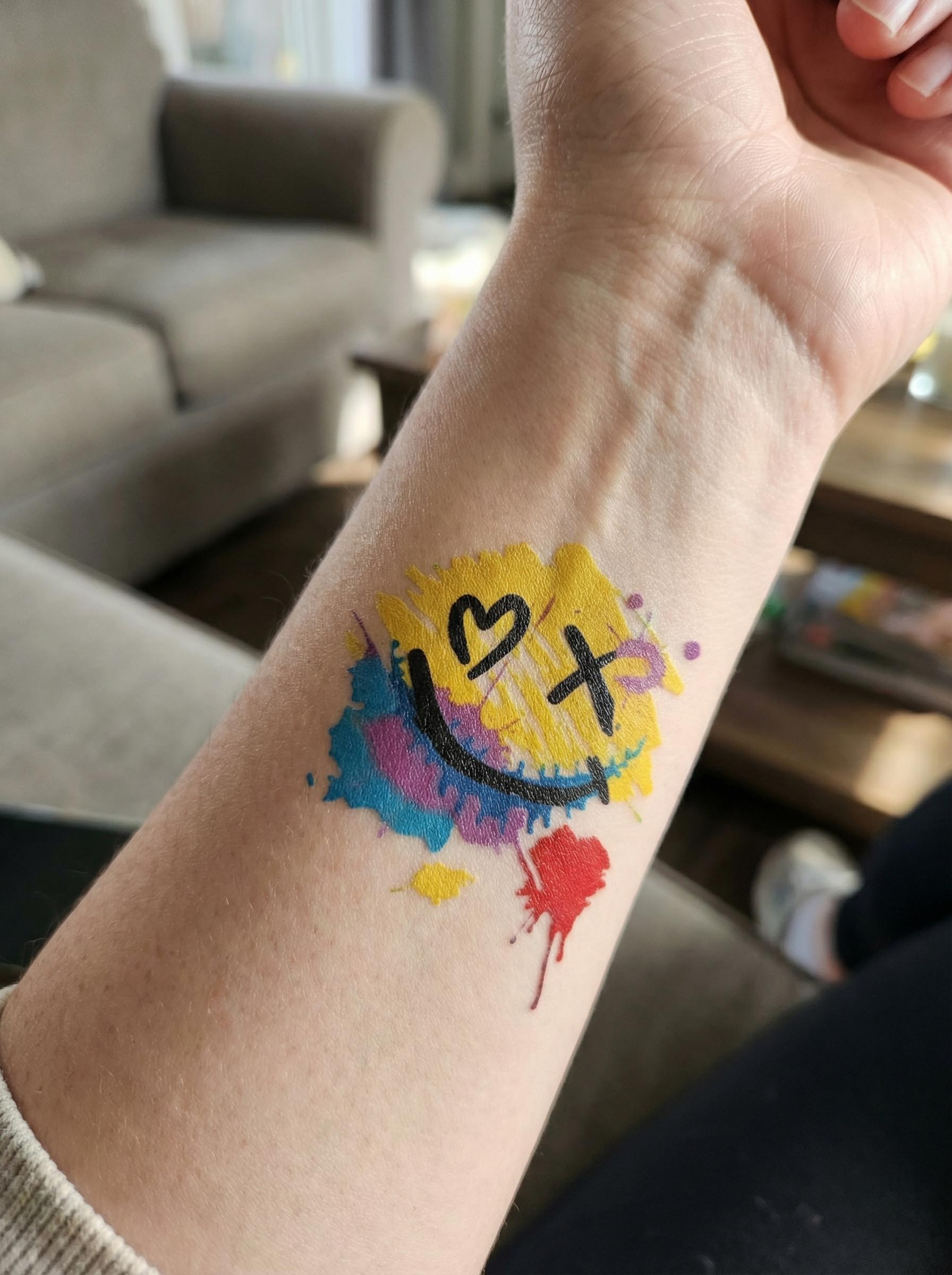 Colorful temporary tattoo applied on wrist with graffiti smiley design
