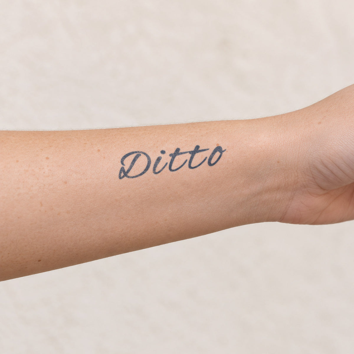 Word temporary tattoos featuring the cursive word “Ditto” in blue-black ink on the inner forearm.