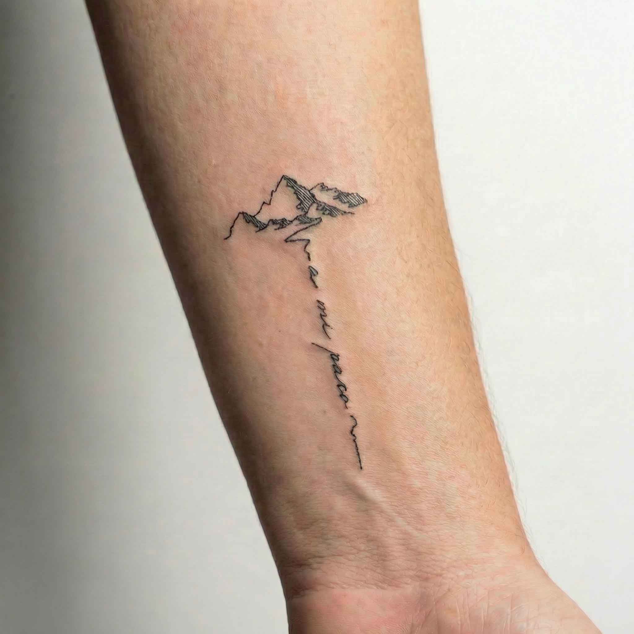 Minimal mountain tattoo worn on the forearm.