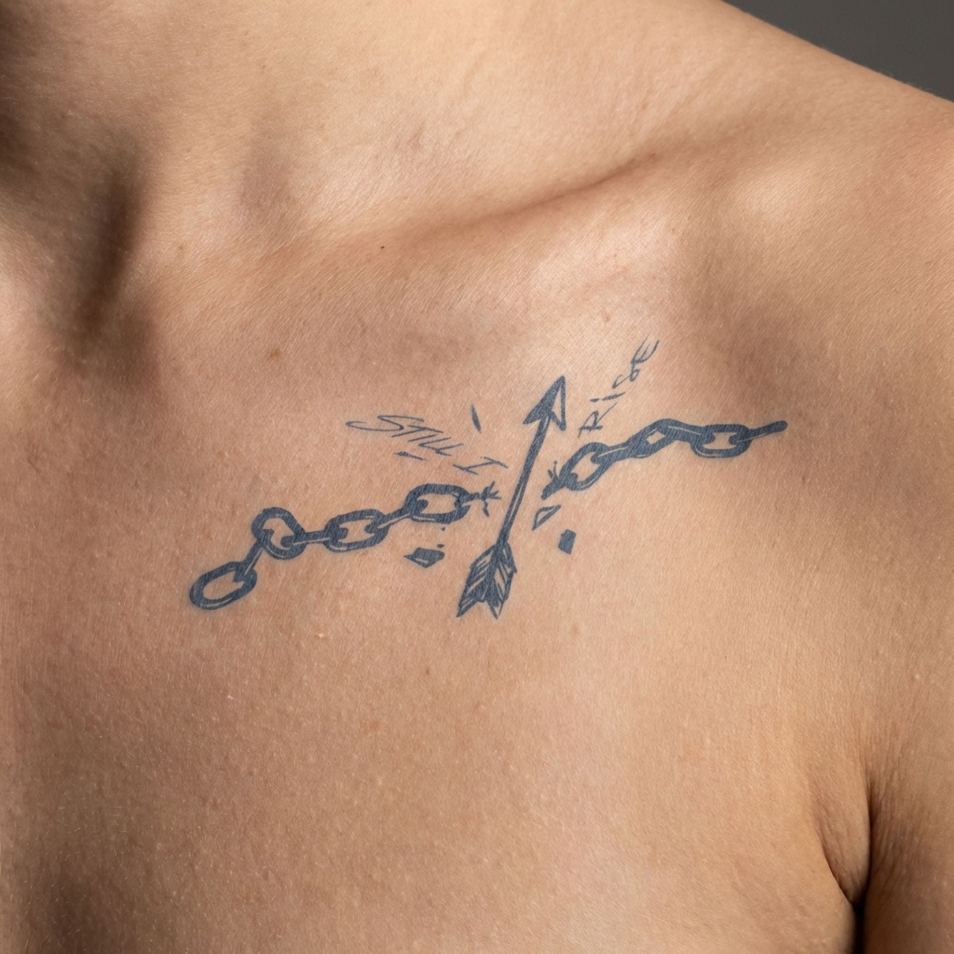 Abstract arrow temp tattoo worn on the clavicle with symbolic broken chain artwork