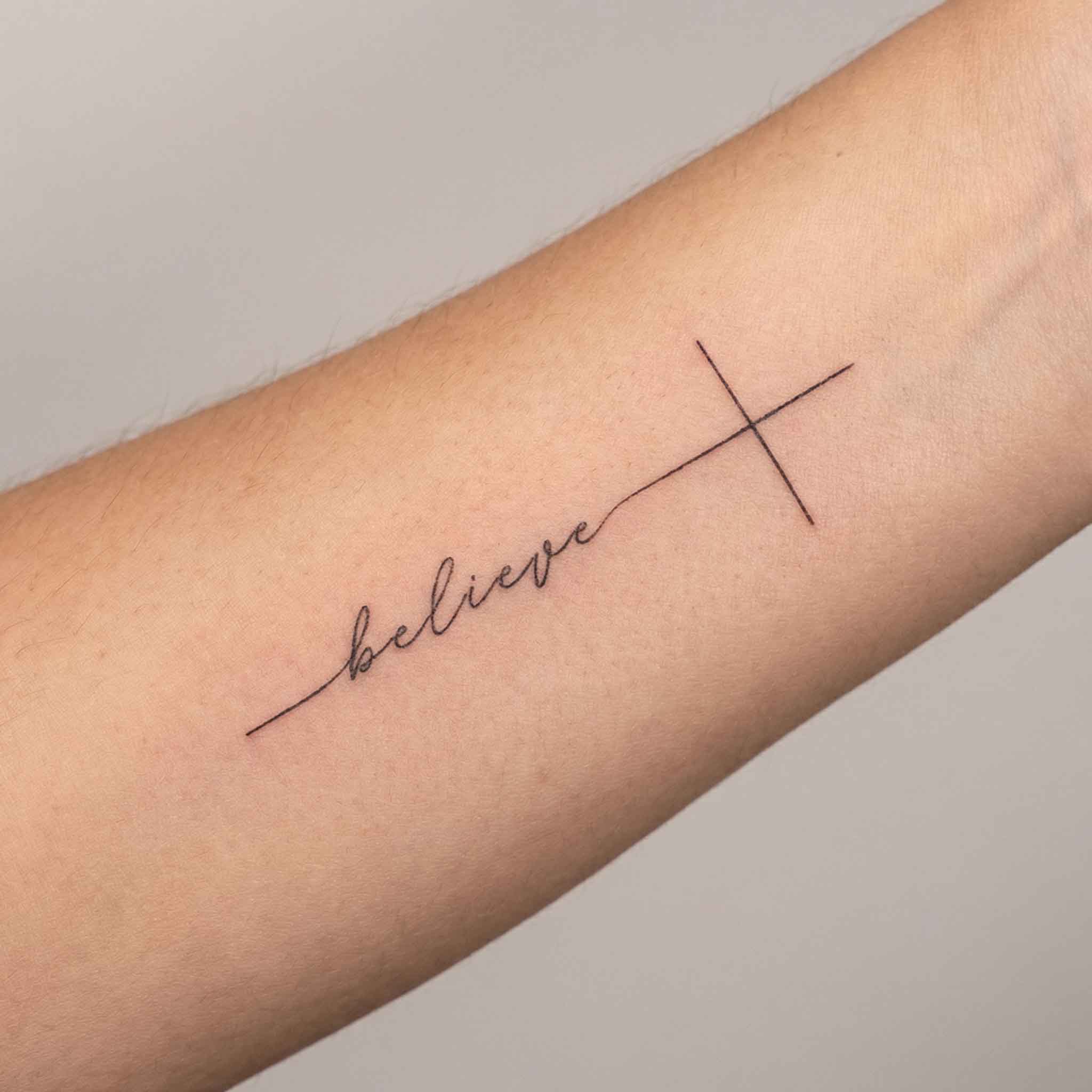 Minimal faith tattoo worn on the wrist.