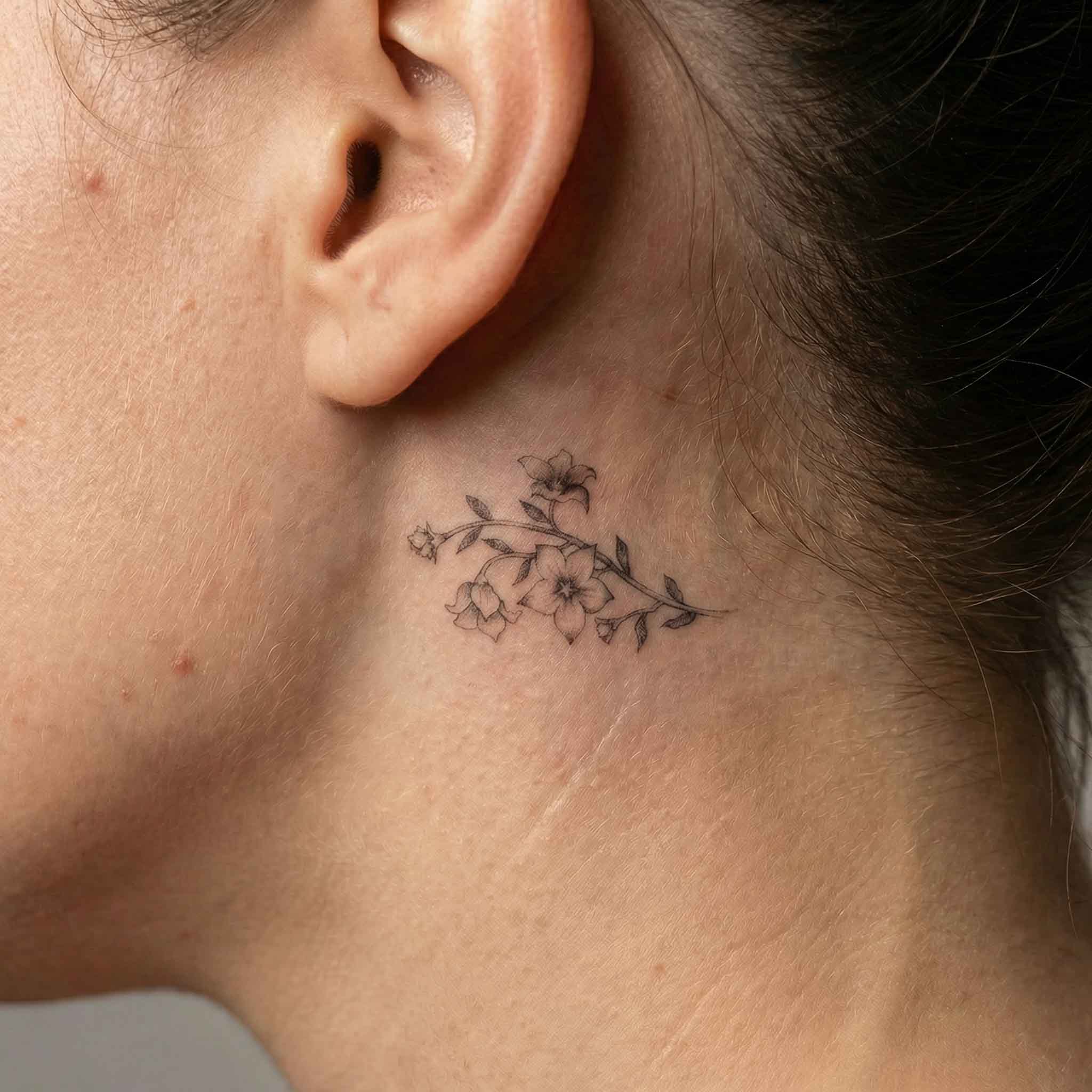 Bellflower temporary tattoo behind ear on skin

