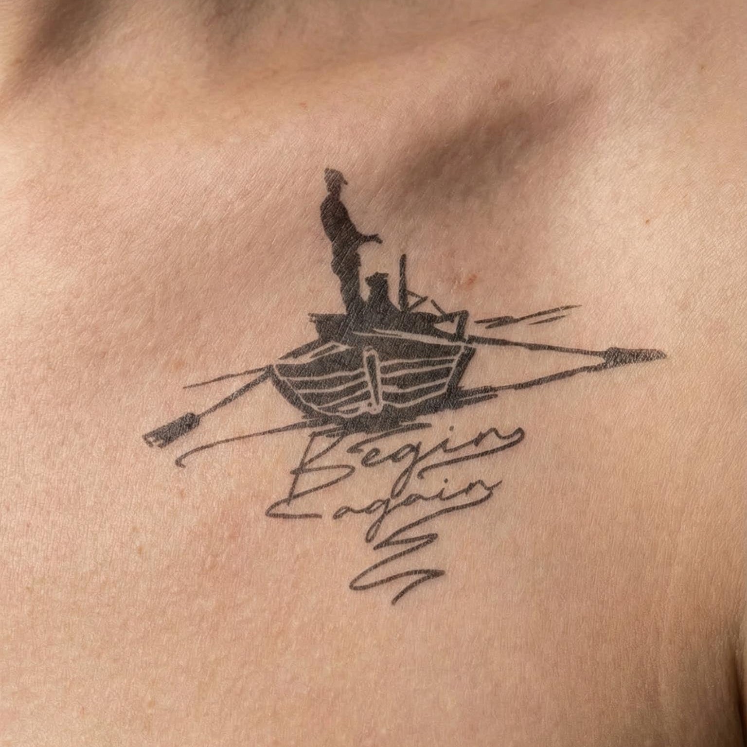 minimalist boat temporary tattoo with text "begin again" fine line design on collarbone