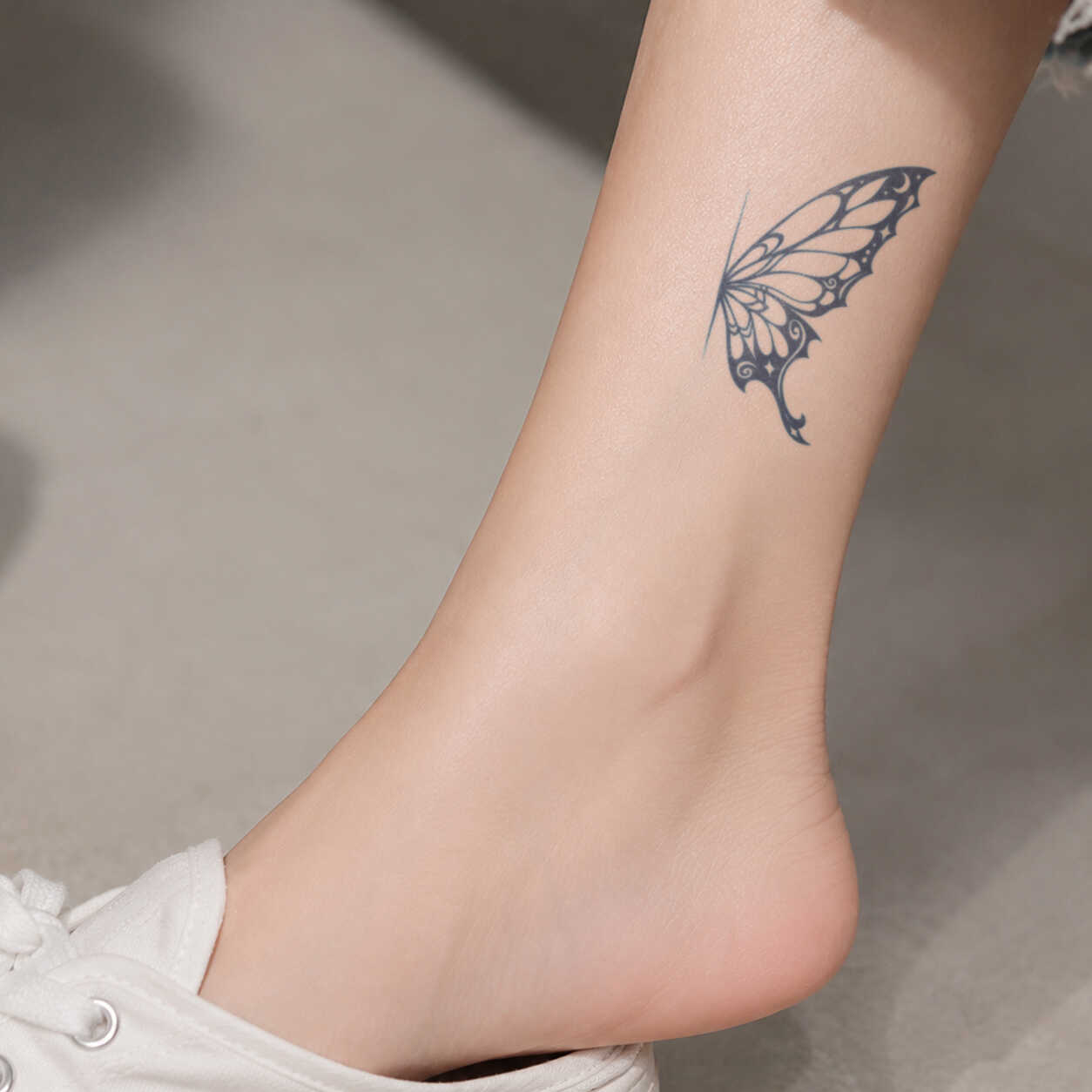butterfly wing temporary tattoo with elegant line details on ankle 