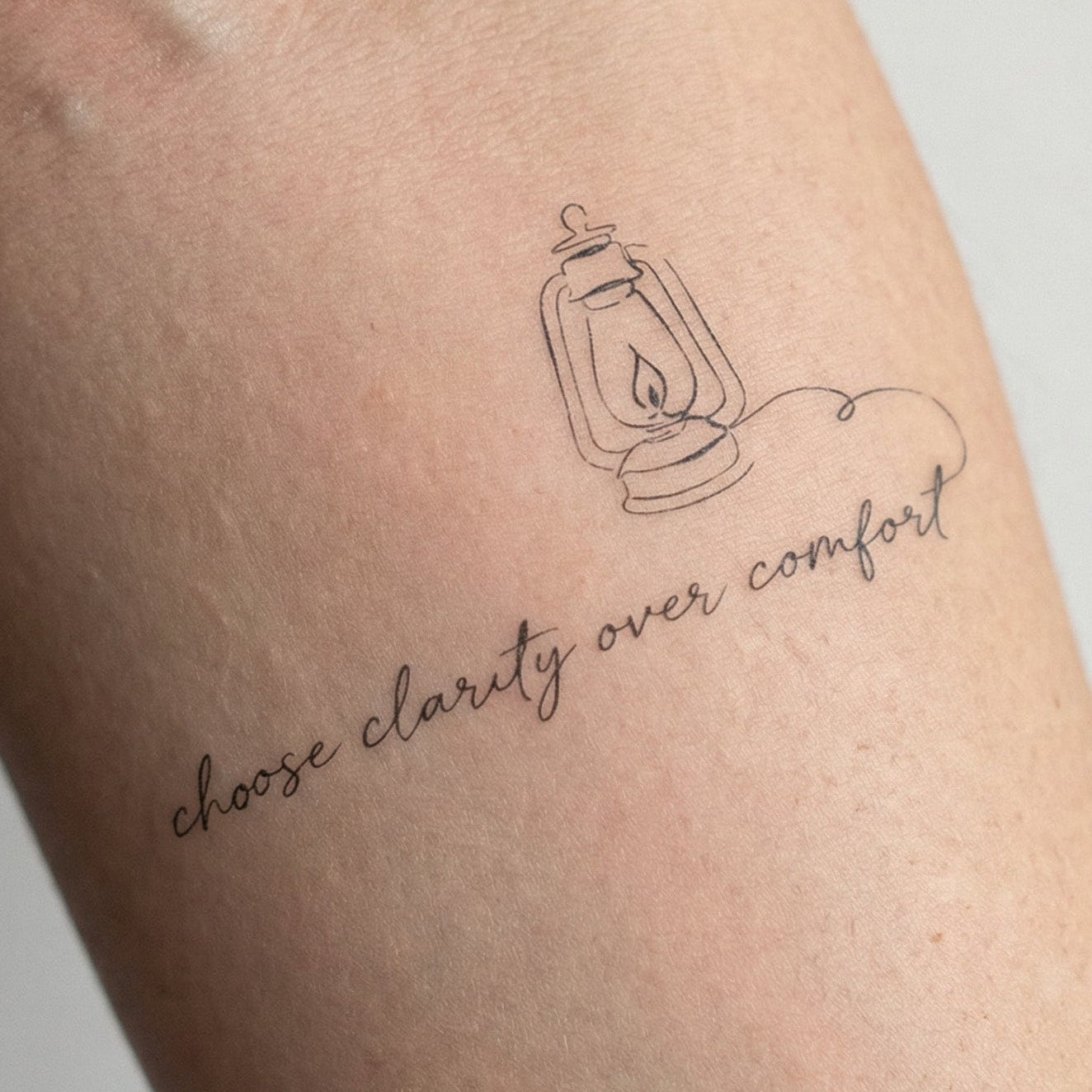 Minimalist script temporary tattoo on the forearm reading “It’s hard to be different” with small birds perched along the lettering.