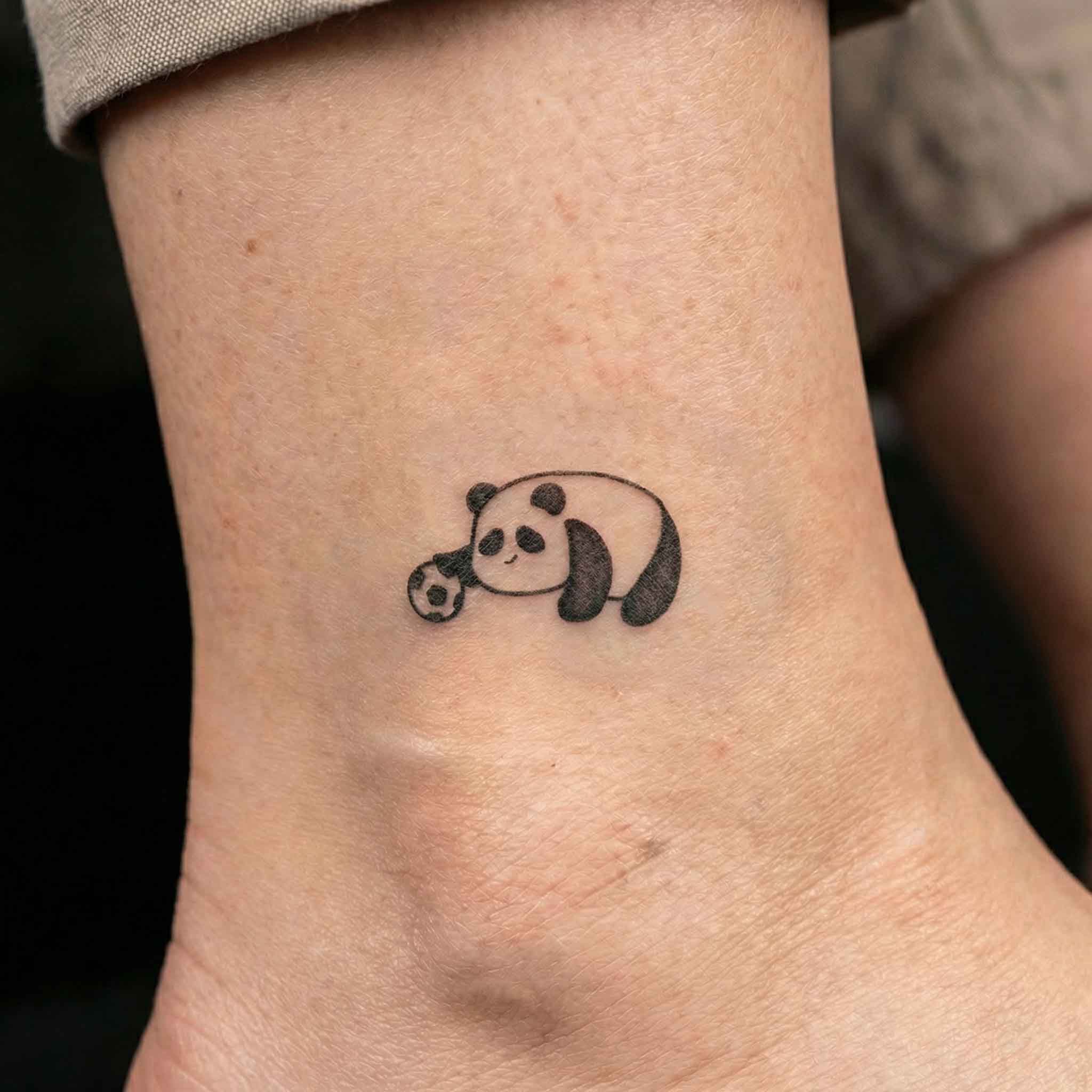 Small panda football tattoo worn on wrist with playful look