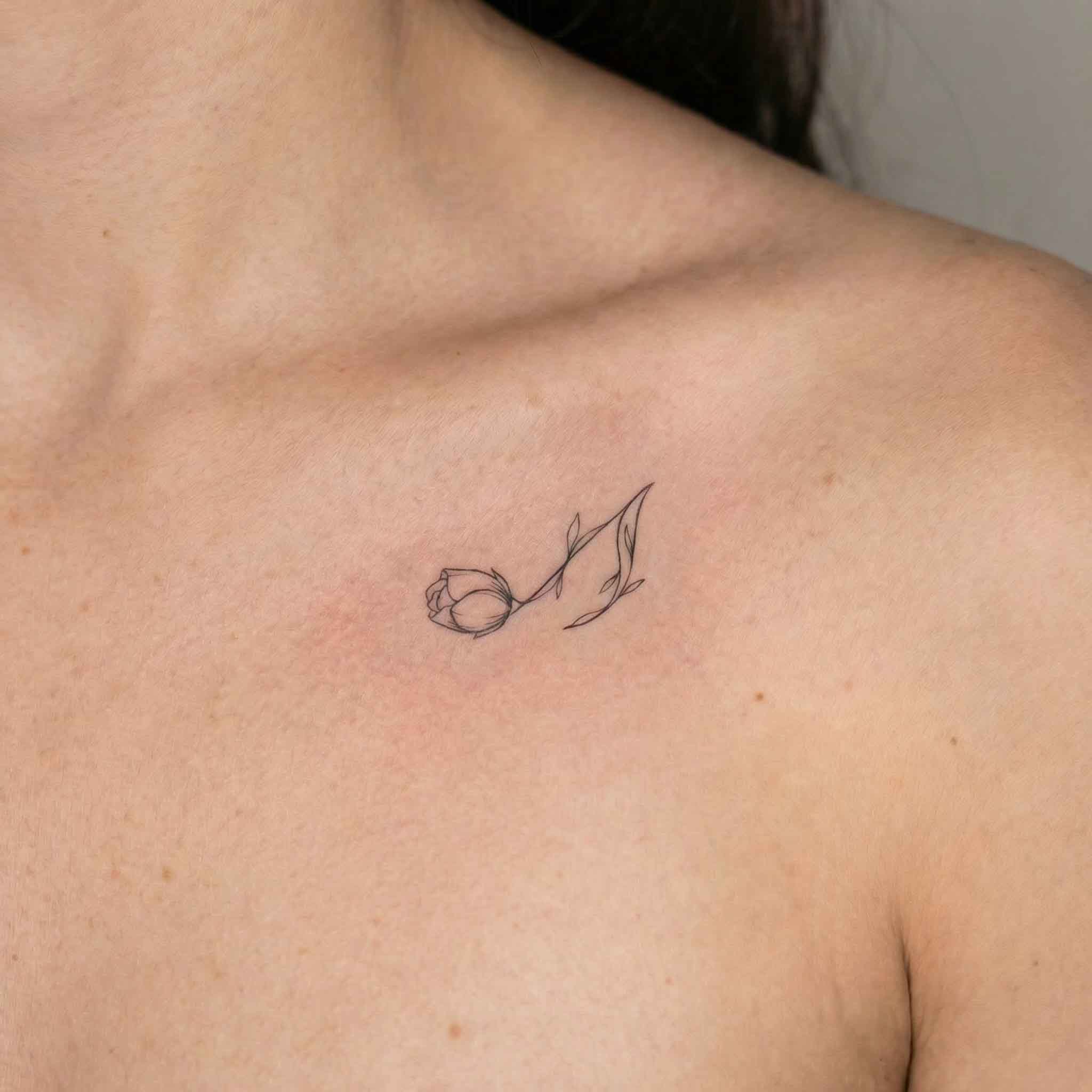 Minimal rose temp tattoo worn on the collarbone with a soft elegant floral look