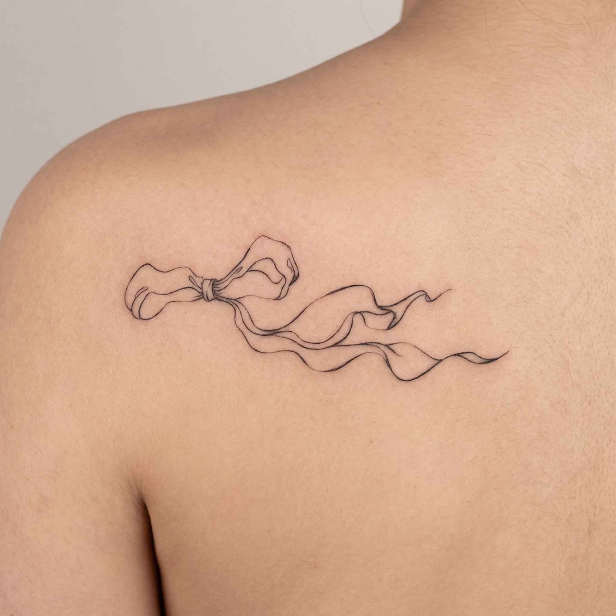 Elegant ribbon tattoo worn on back with soft fine line details