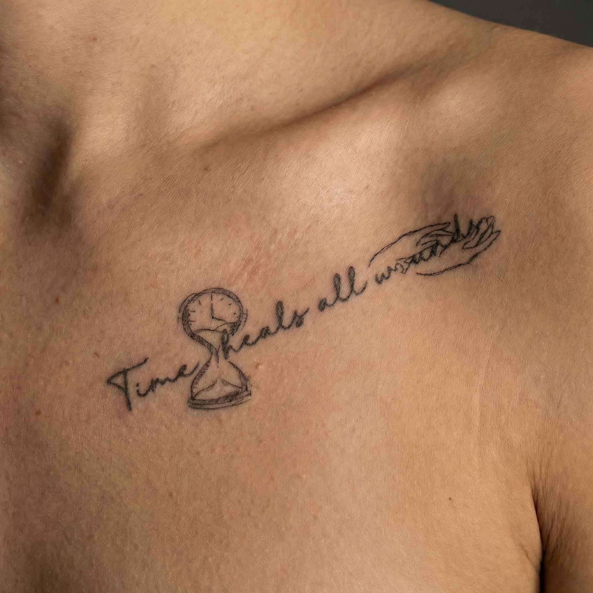 Minimal healing quote tattoo placed along collarbone with fine line details