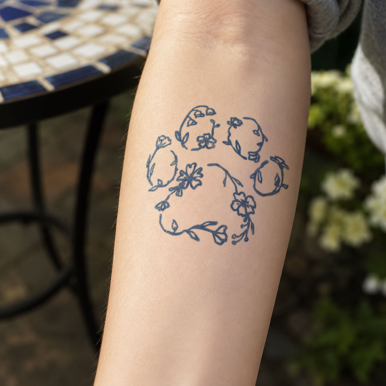 Temporary forearm tattoos featuring a dog paw print formed from garland.
