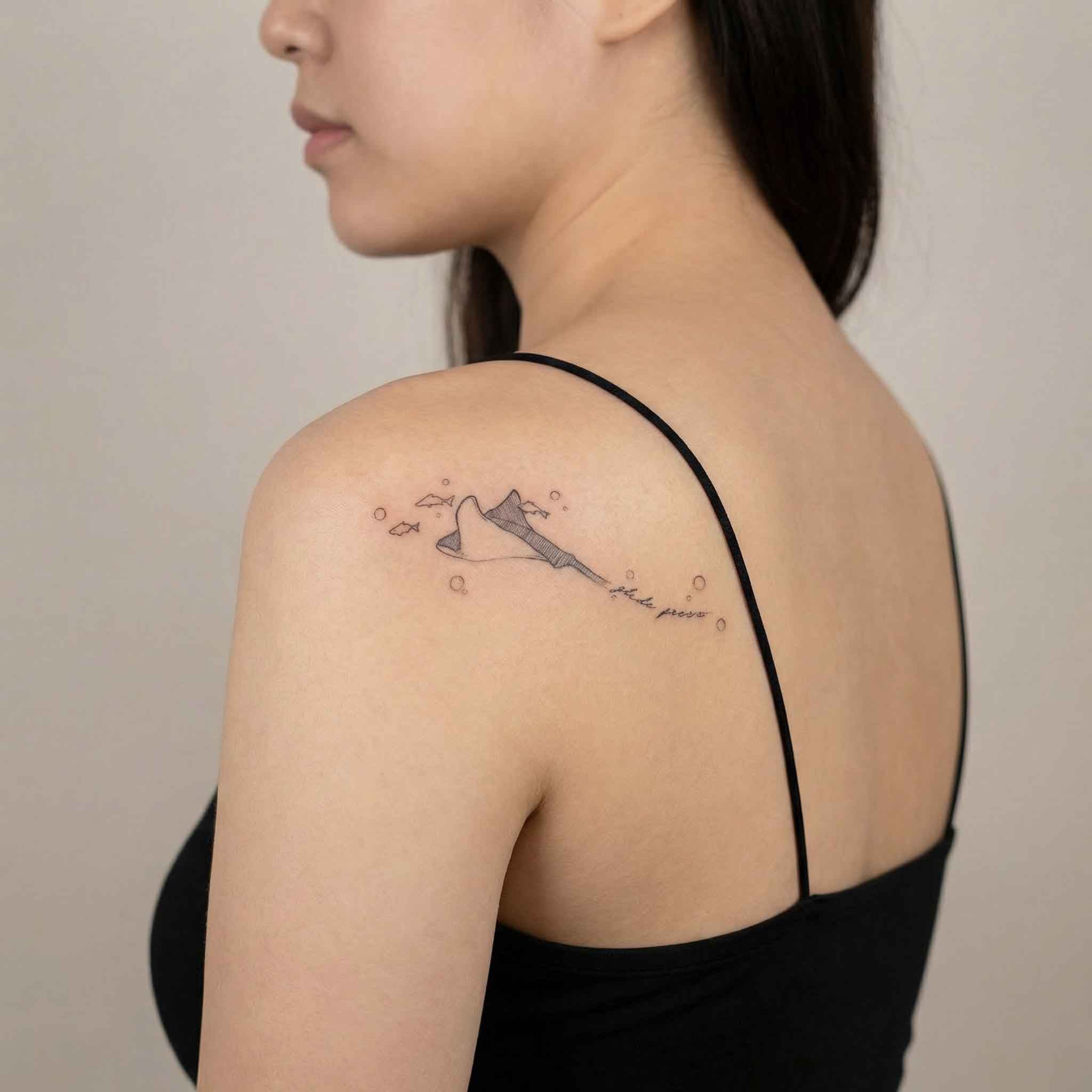 Fine line manta ray tattoo worn on back with ocean bubble details