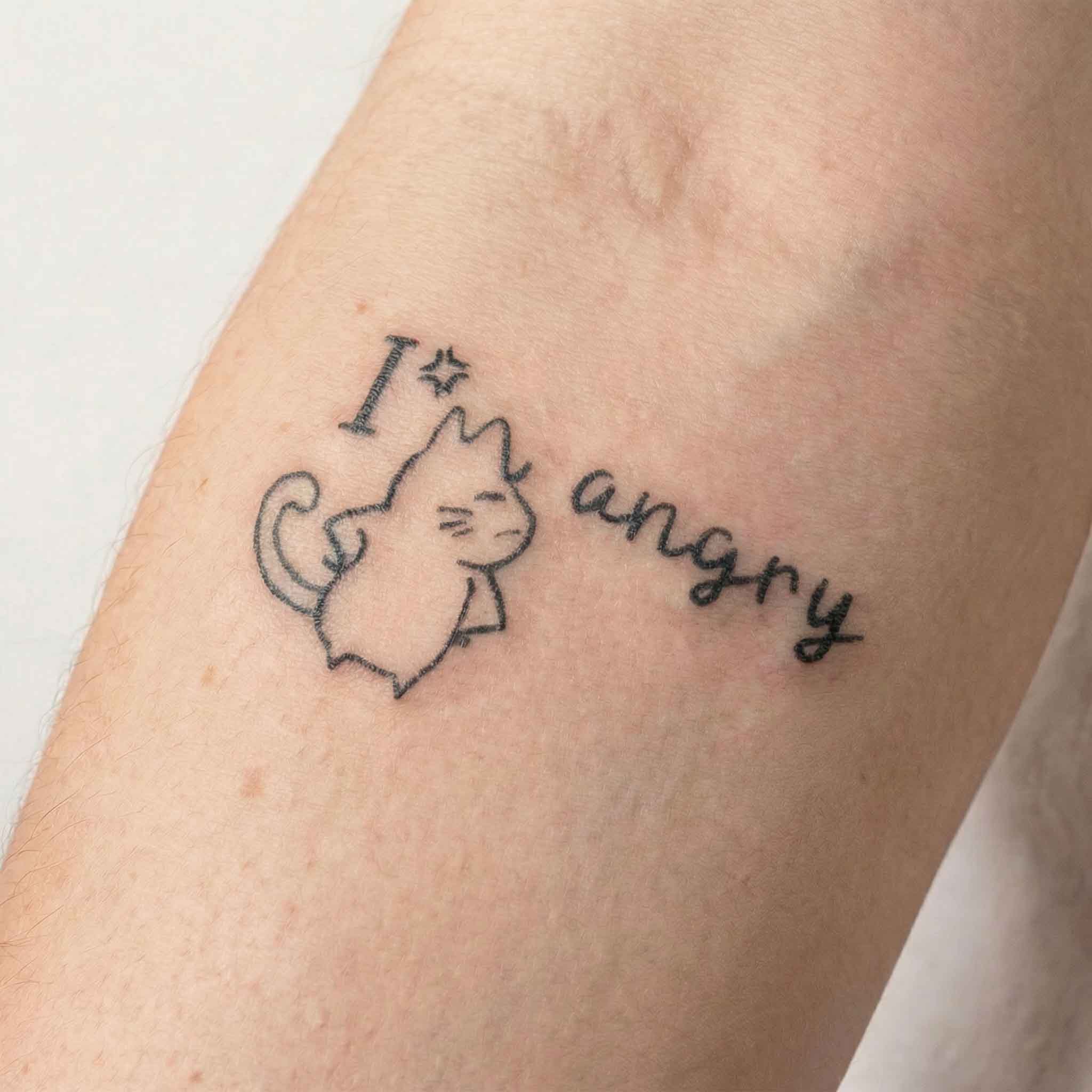 Funny cat tattoo worn on the wrist with playful handwritten wording