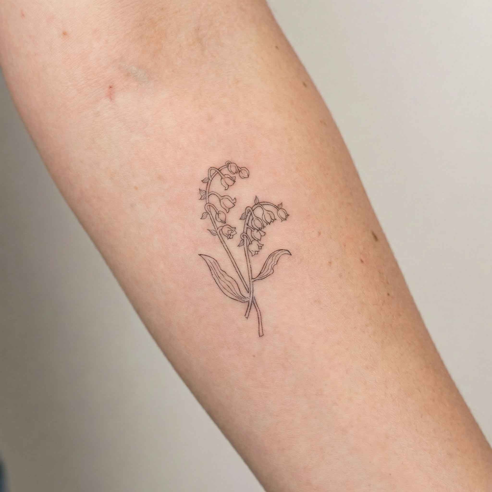 Fine line lily of the valley tattoo worn on forearm in botanical style