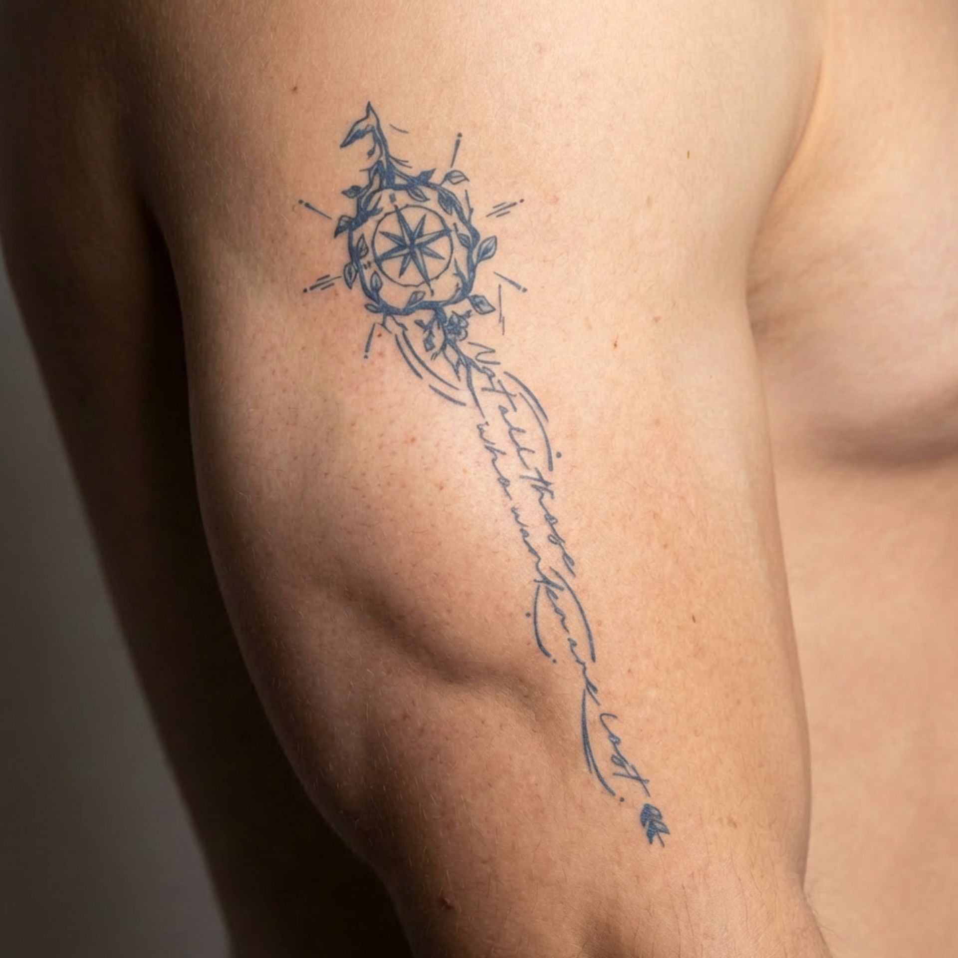 Temporary tattoo of compass and upside-down bird with inspirational quote on wrist