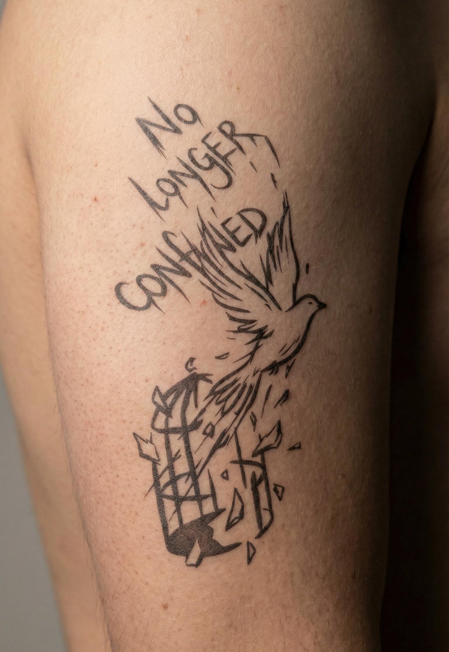 broken cage bird temporary tattoo with text "no longer confined" minimalist freedom tattoo on arm