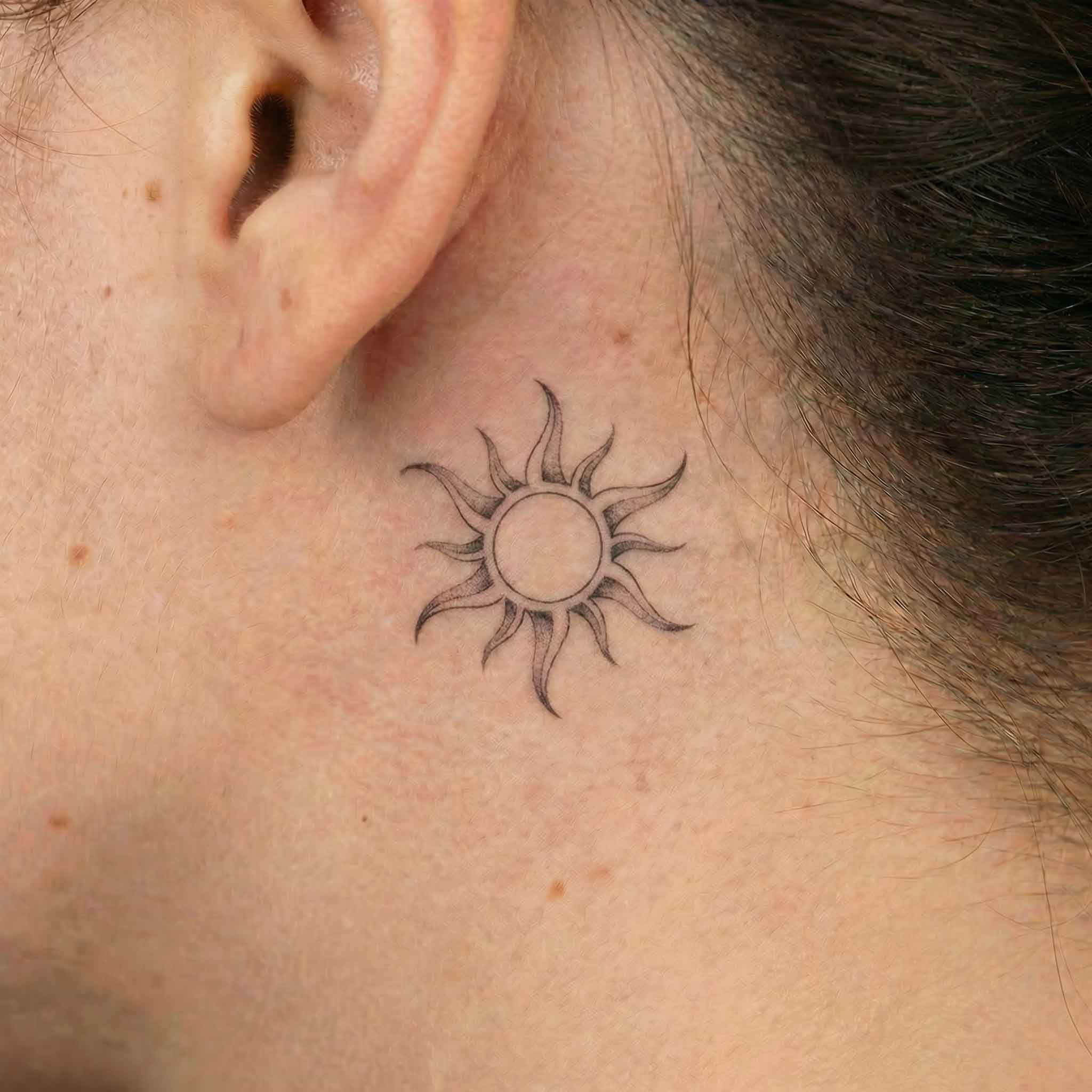 Minimal sun fake tattoo worn behind the ear with a clean natural look