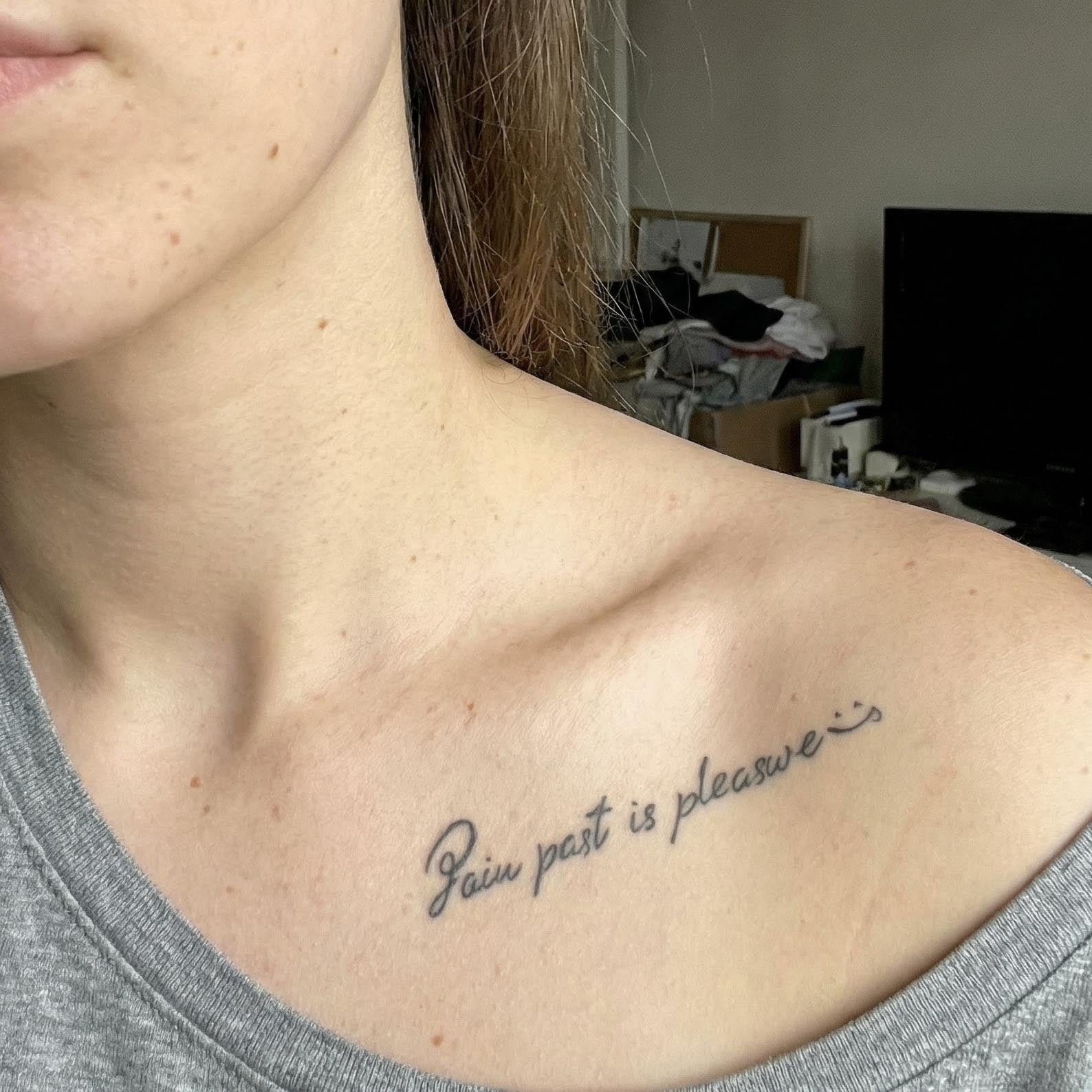 Elegant script temporary tattoo on the collarbone reading “Pain past is pleasure”, minimalist handwritten style inspirational quote tattoo.