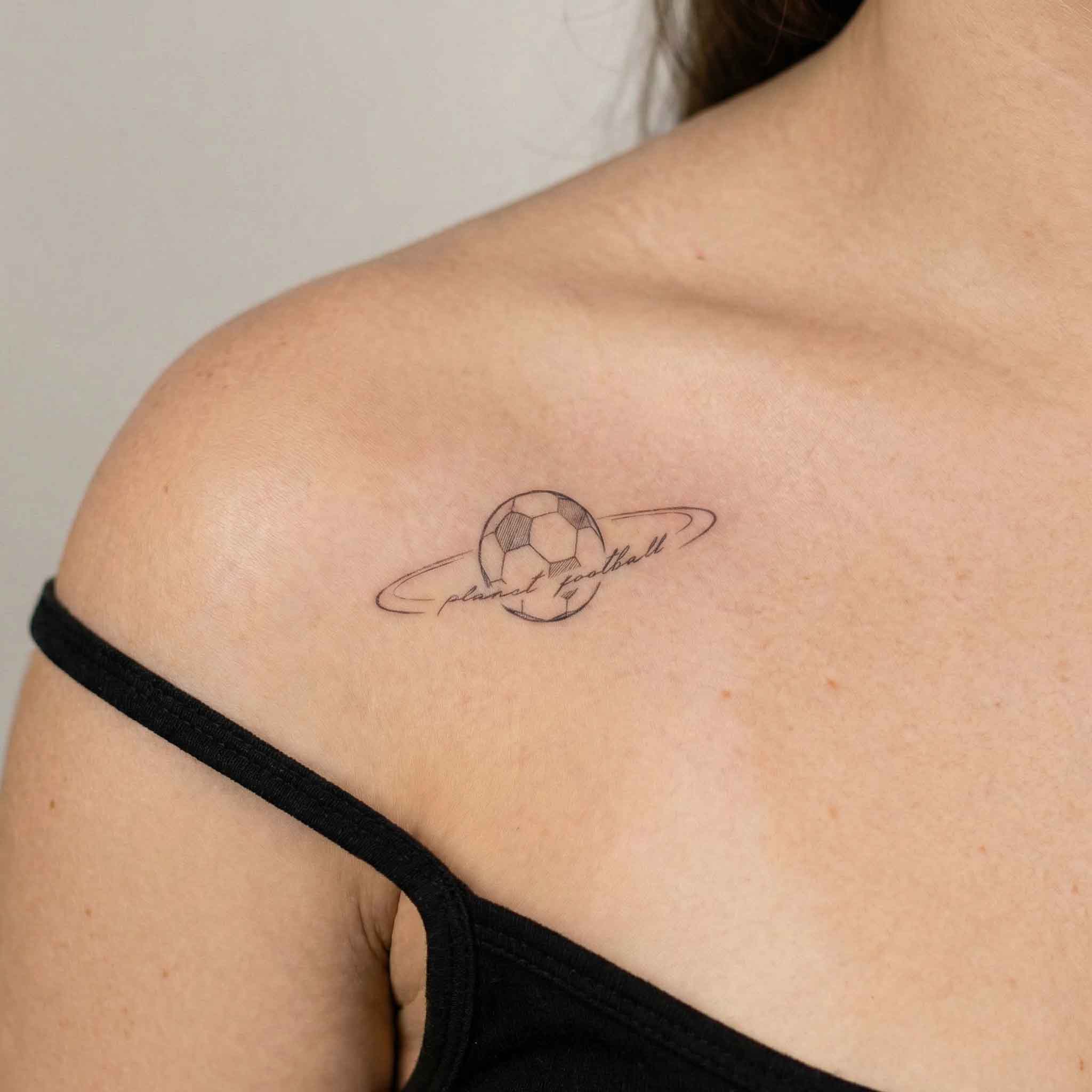 Minimal soccer planet tattoo worn on clavicle with sporty line art