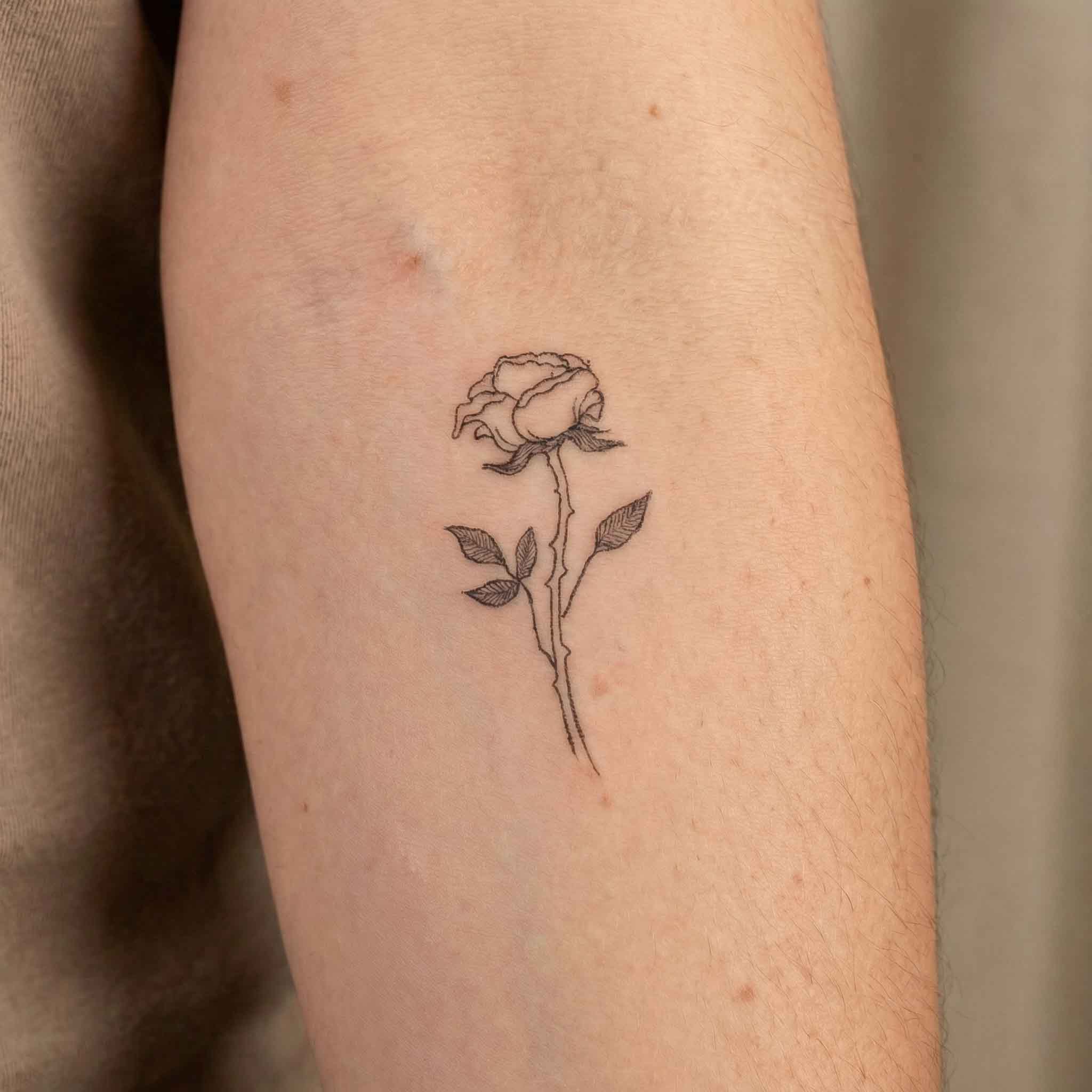 Minimal rose tamp tattoo on arm with elegant floral details