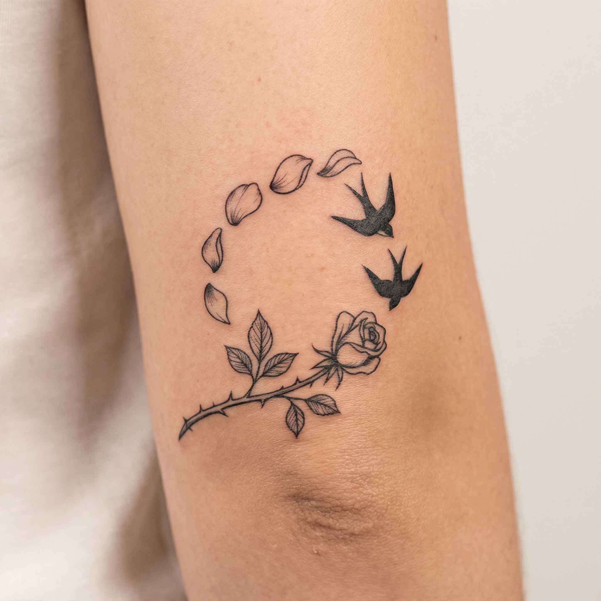 Floral swallow temporary tattoo worn on the upper arm with delicate linework