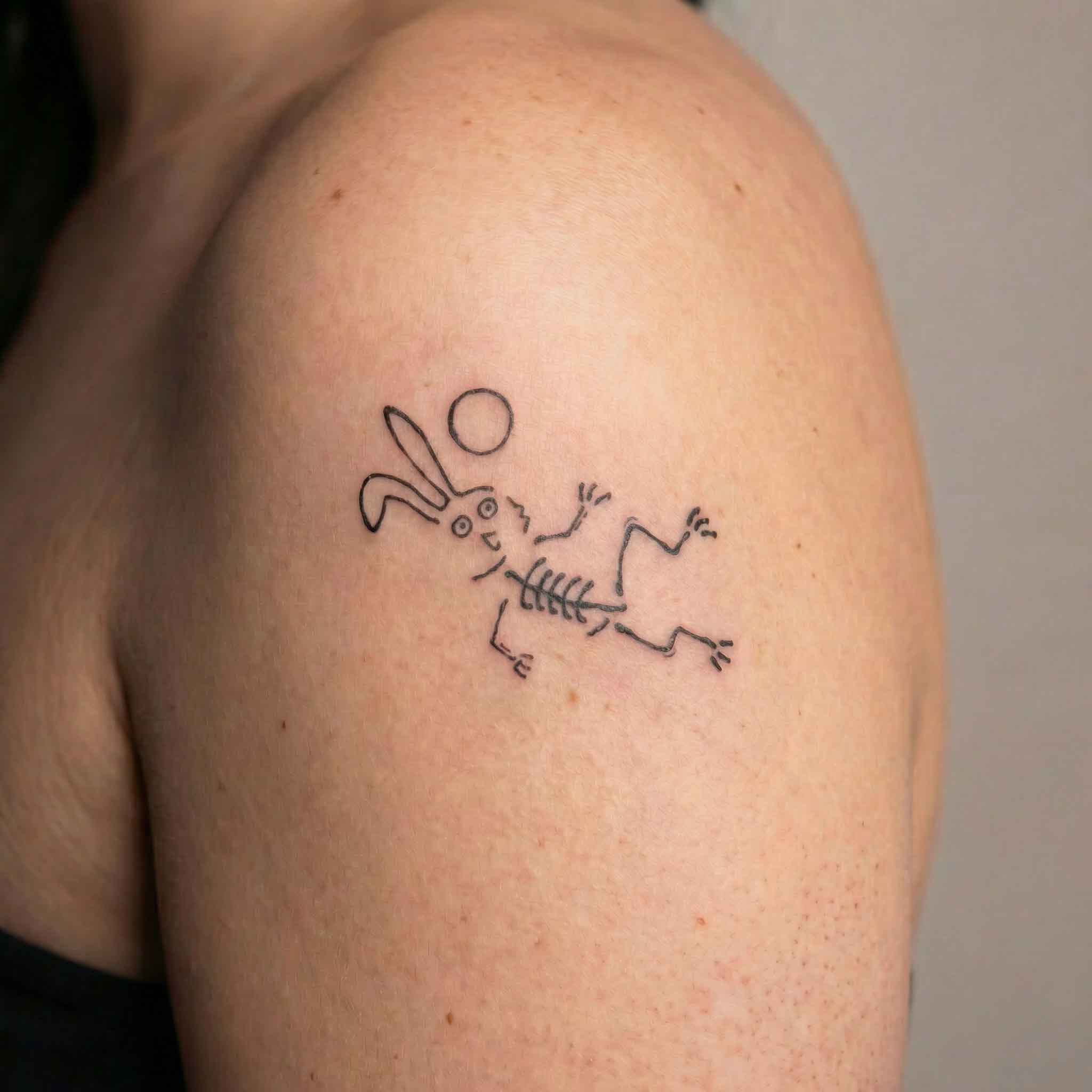 Small skeleton bunny tattoo worn on arm in minimalist playful style