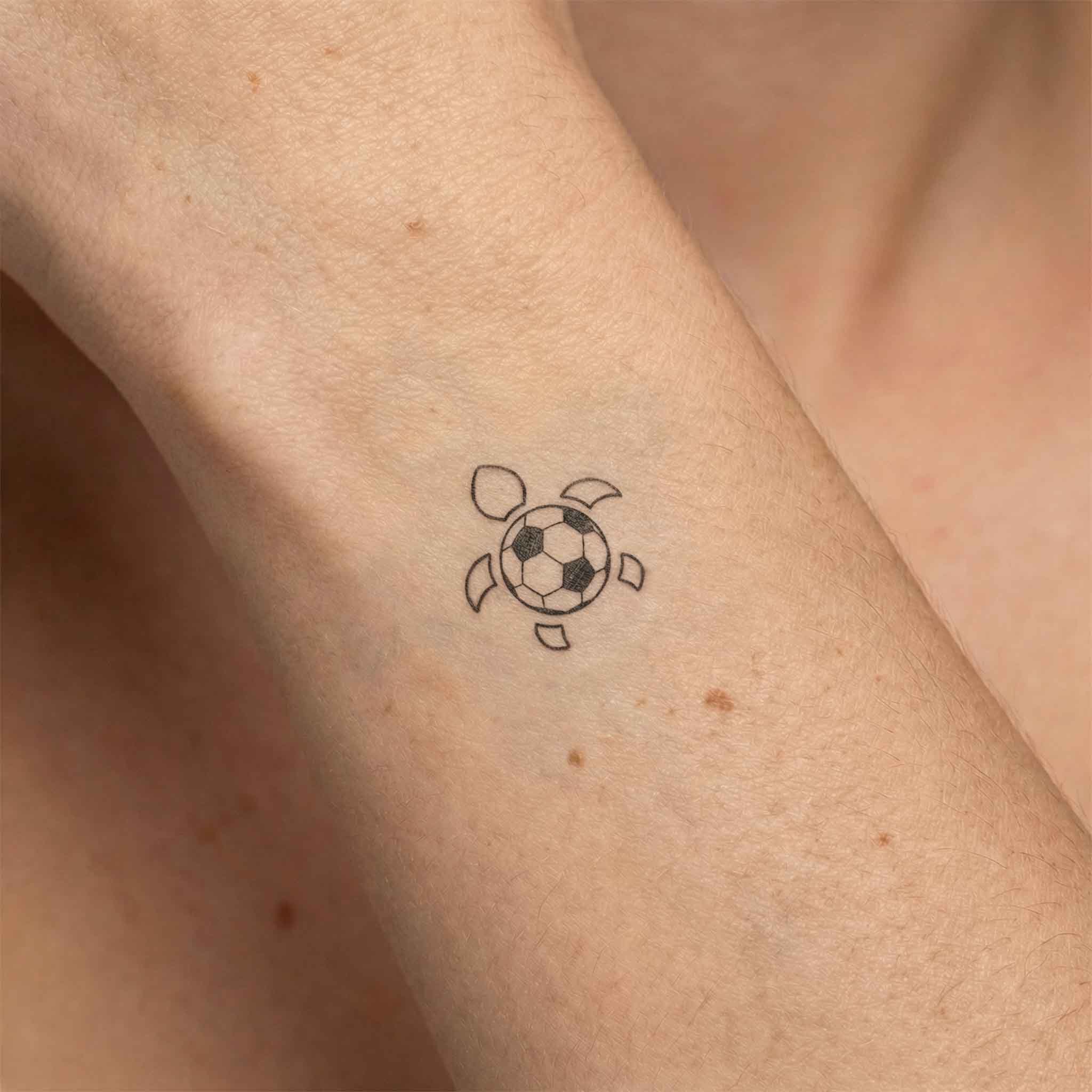 Cute football turtle tattoo worn on arme in fine line style