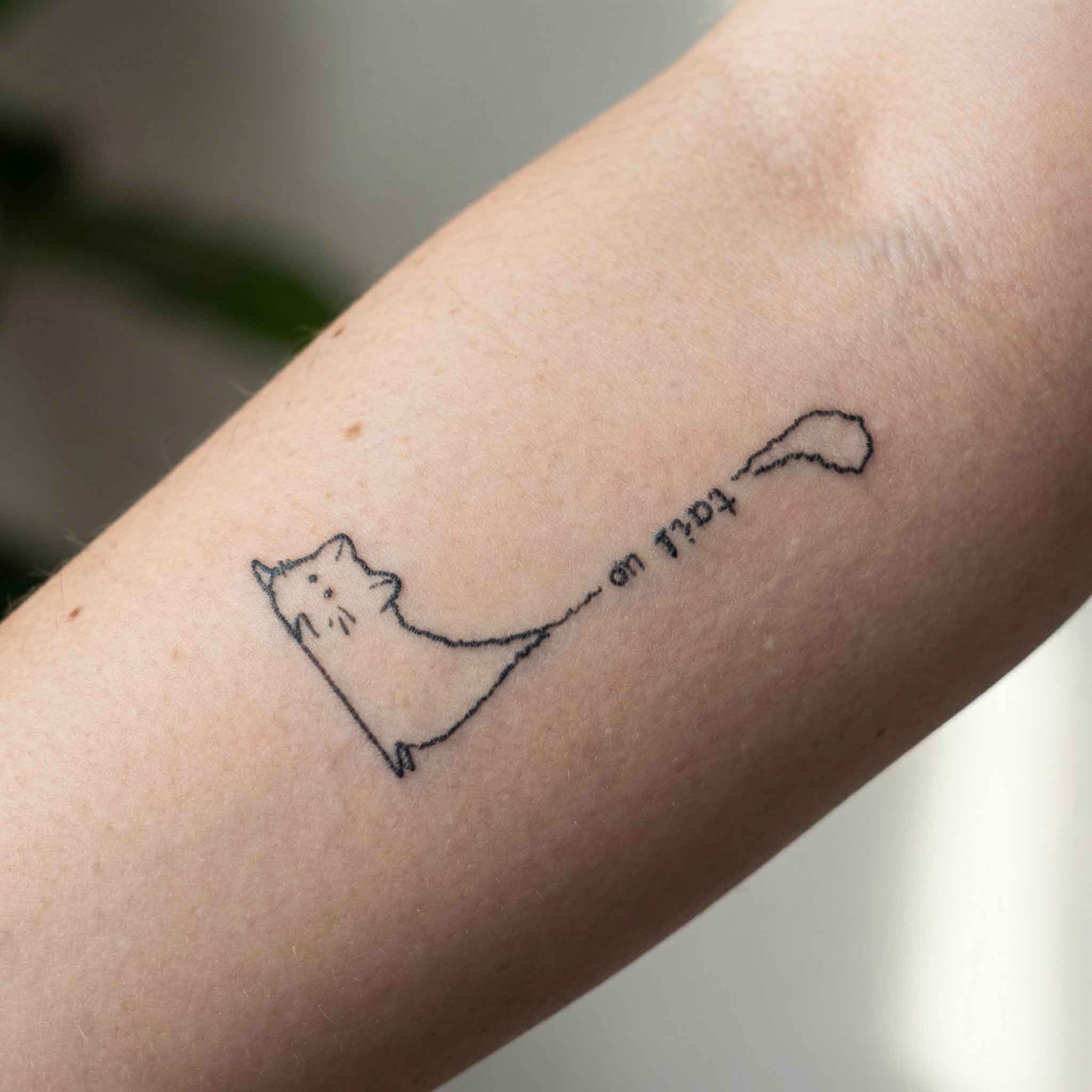 Small cute cat temp tattoo worn on wrist in simple fine line style