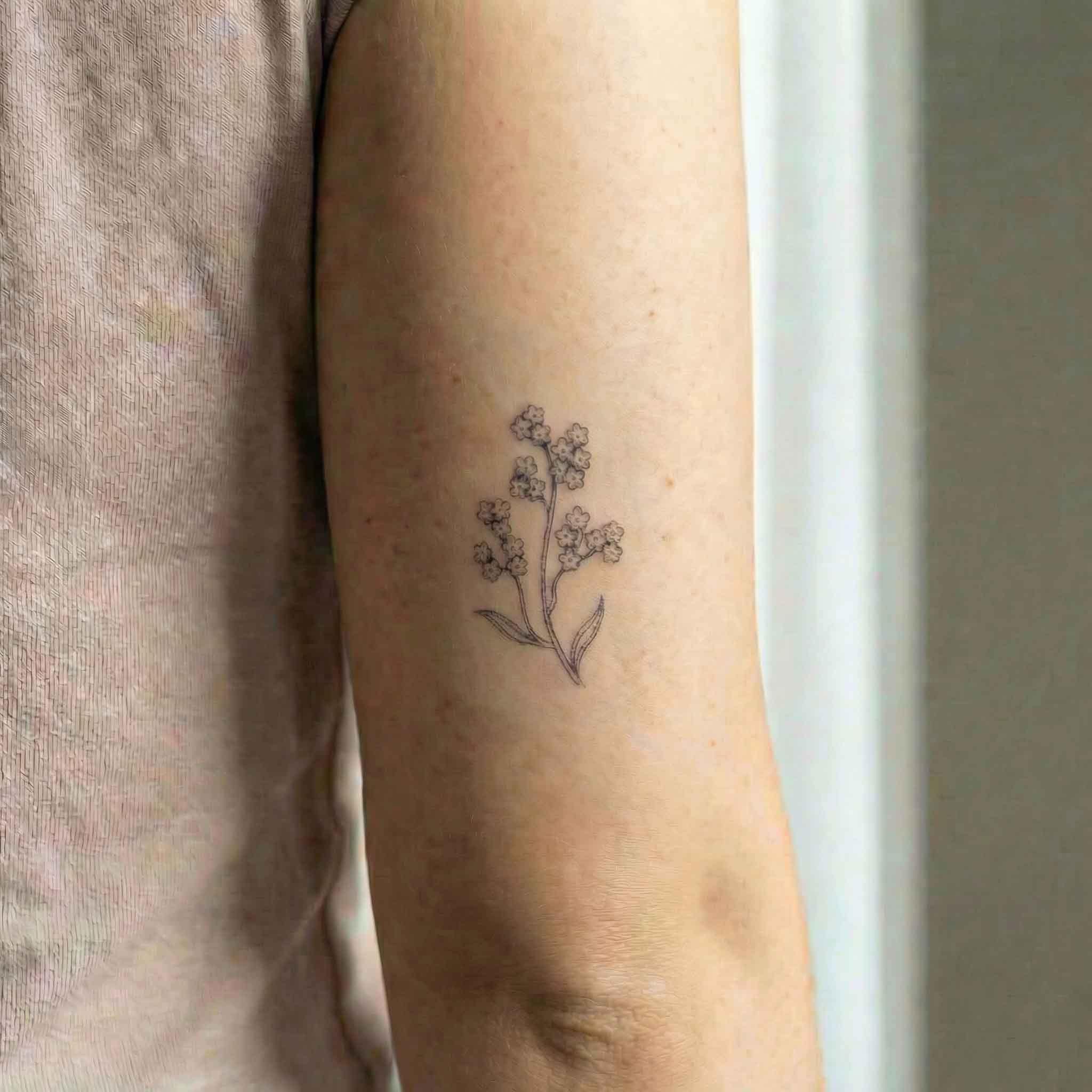 Minimal wildflower tattoo worn on arm