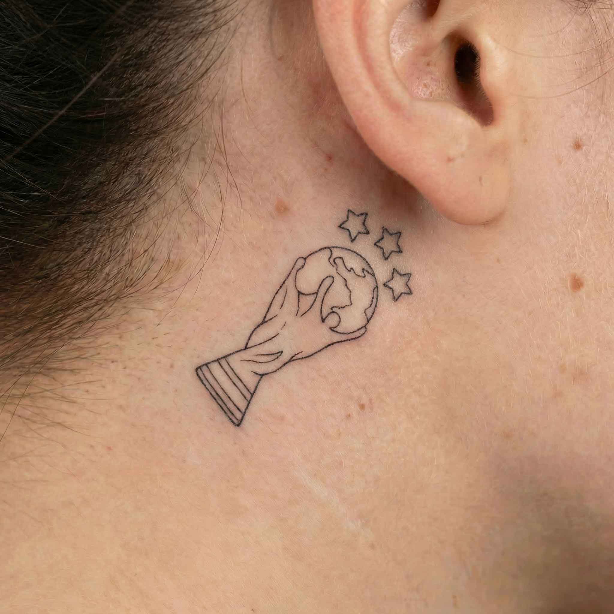 Minimal World Cup temp tattoo worn behind the ear with clean trophy design