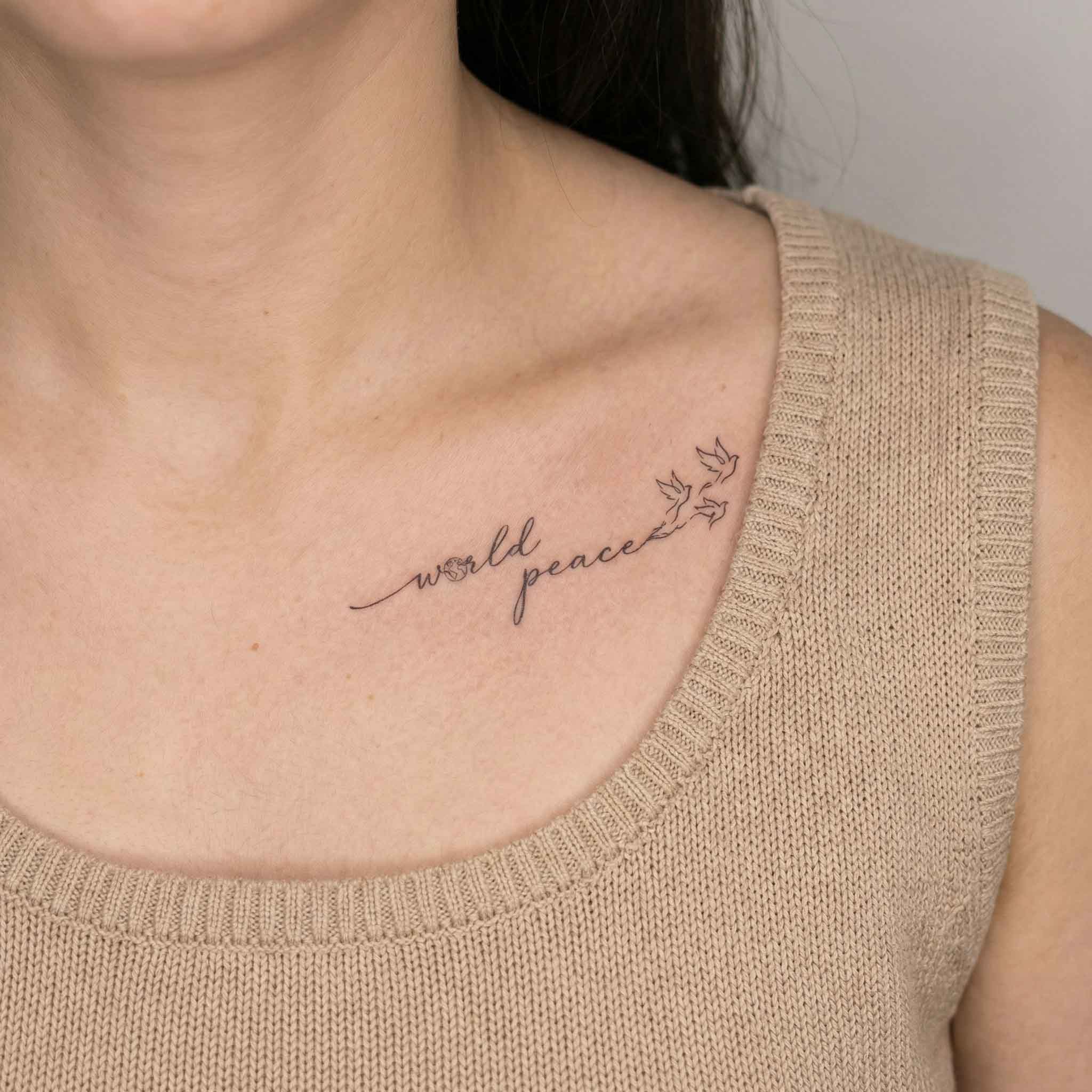 Dove and globe temp tattoo worn on the clavicle with simple word detail